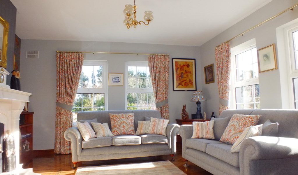 Bright living room with orange and white curtains and pillows