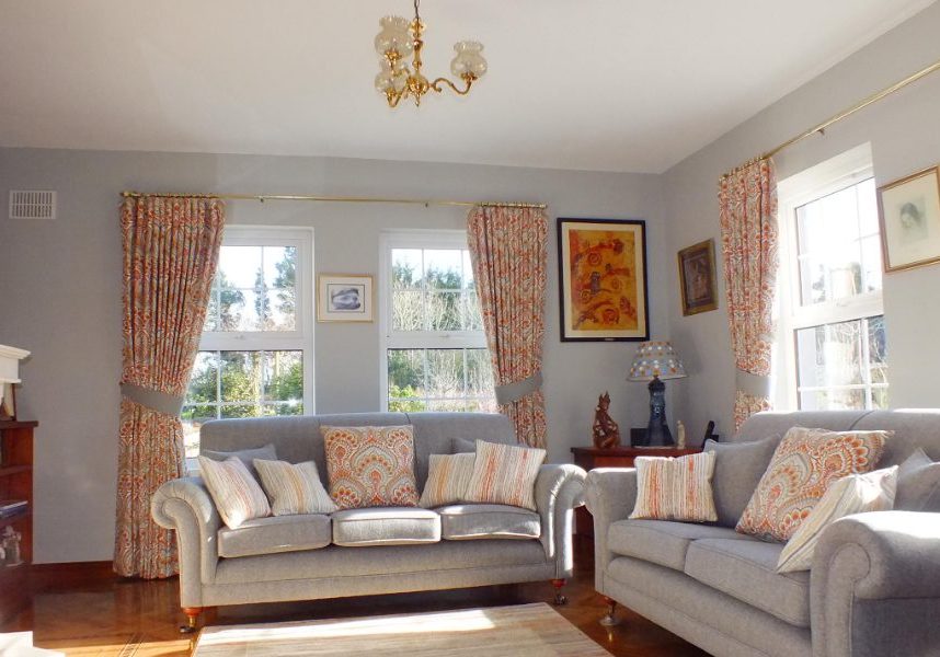 Bright living room with orange and white curtains and pillows