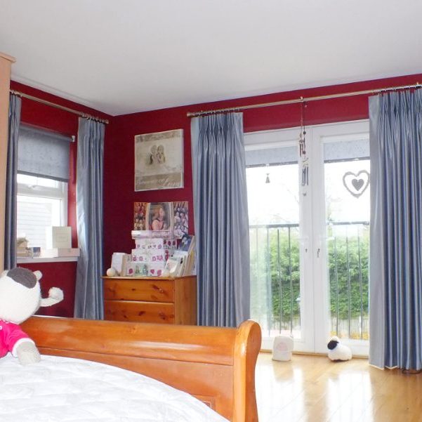 Girls bedroom with red walls and blue/silver curtains on balcony