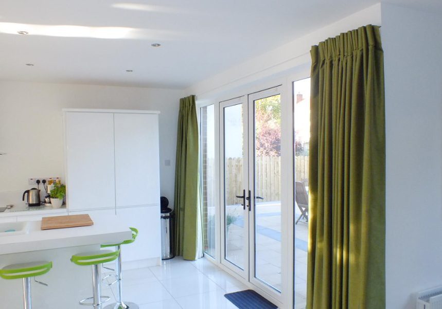 Open plan kitchen with green curtains and green bar stools